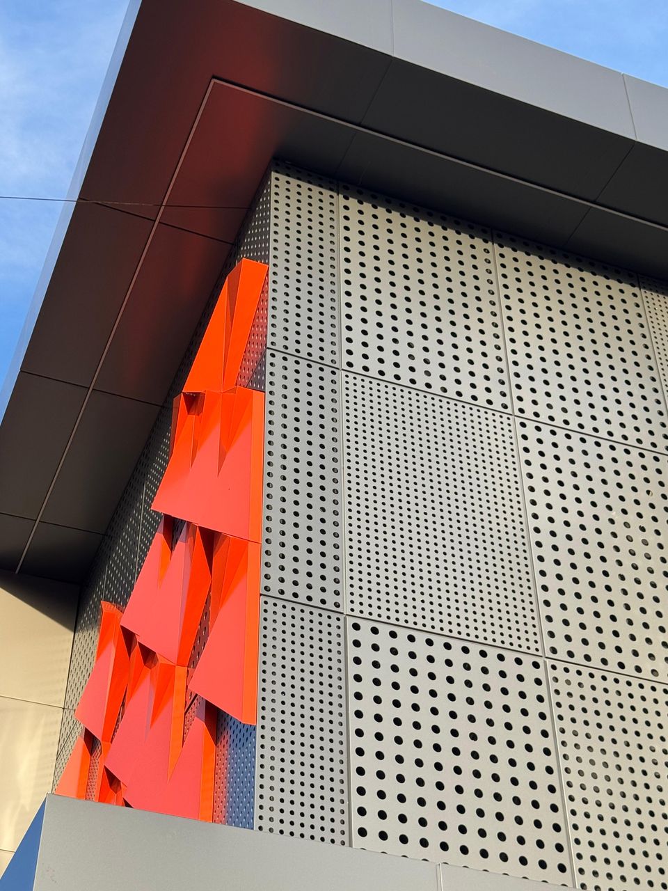 Orange folded pieces beside a perforated screen